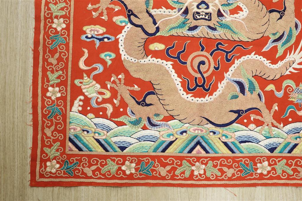 A early 20th century Chinese red felt square panel embroidered with a central motif of a dragon, width 86cm height 84cm